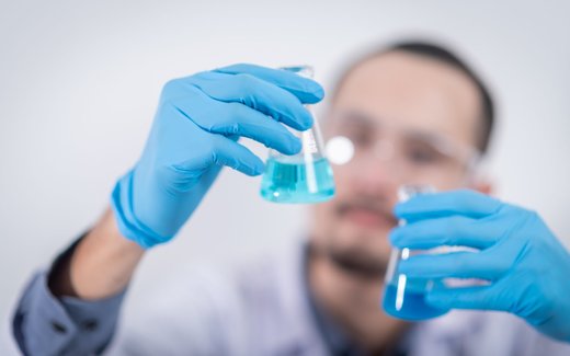 Two researchers in a laboratory examine a blue-tinted flask together