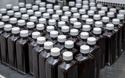 Rows of capped amber oral-liquid bottles on a production line at Cosette Pharmaceuticals' manufacturing operation