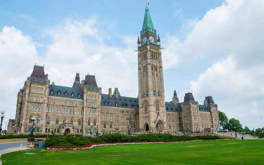 The Peace Tower and Centre Block of Canada's Parliament Hill in Ottawa under a blue sky