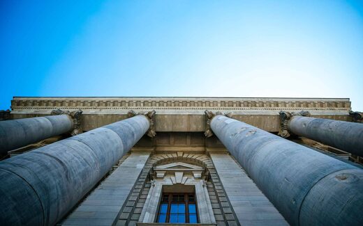 Classical columns of a government building viewed from below against a blue sky