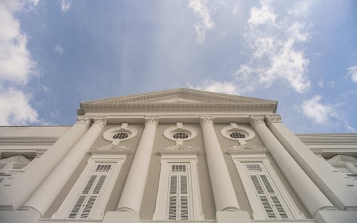 A neoclassical government building's columns and pediment against a blue sky