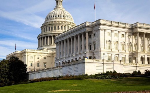 The US Capitol building with its dome and colonnade under a bright blue sky