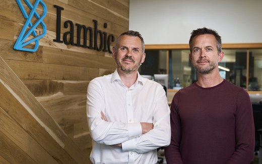 A professional smiles in an outdoor portrait, standing in for the Iambic Therapeutics team marking its Nasdaq debut