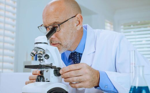 A scientist examines a sample under a microscope in a bright laboratory