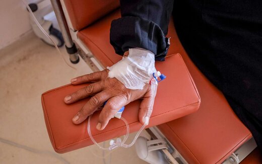 A patient's bandaged hand resting on an infusion-chair armrest, an IV line in place, standing in for Jemperli's intravenous dosing