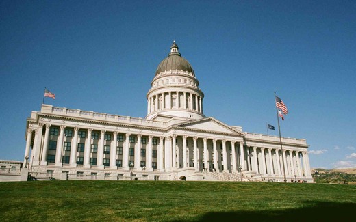The Utah State Capitol building under a clear blue sky, with American flags flying in front