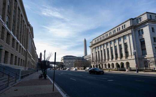Federal office buildings along a Washington, D.C. street, with the Washington Monument visible in the background