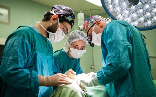 A surgical team works together under bright operating lights during a vascular procedure