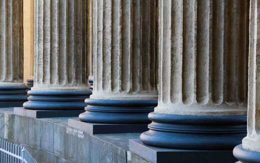 Fluted stone columns of a classical institutional building in sunlight