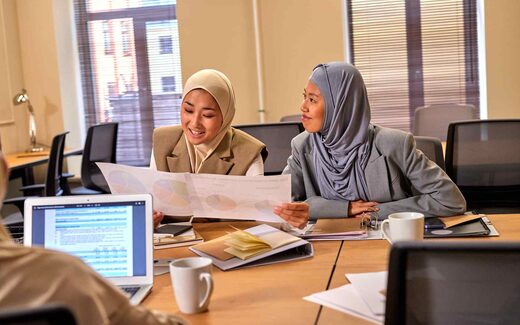 Two colleagues review a printed chart of data together at a conference table