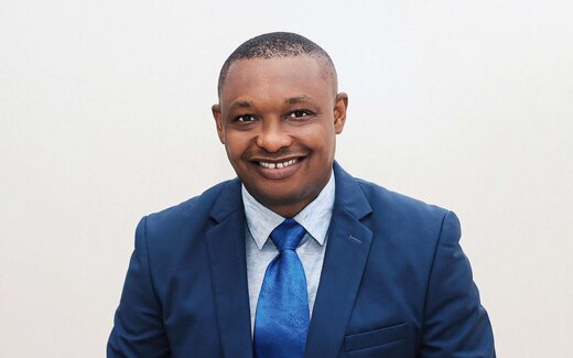 A smiling professional in a blue suit poses for a studio portrait