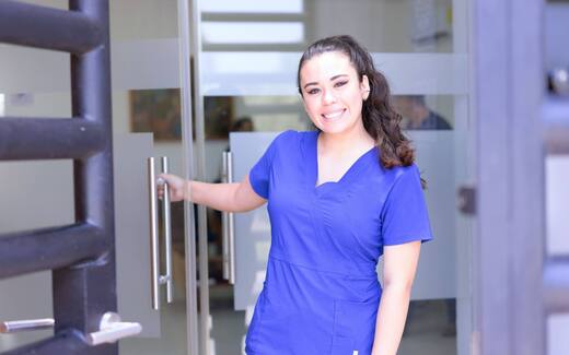 A clinician in scrubs at a clinic entrance