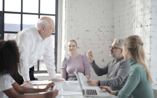 A small team gathers around a table in a bright, modern loft-style office