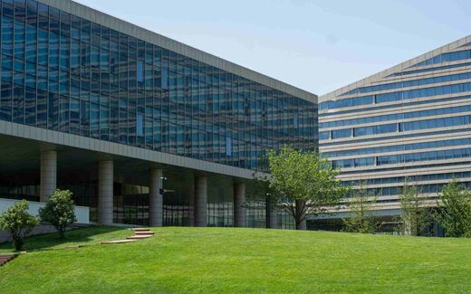 Exterior of a modern glass-and-concrete corporate campus building under a clear blue sky