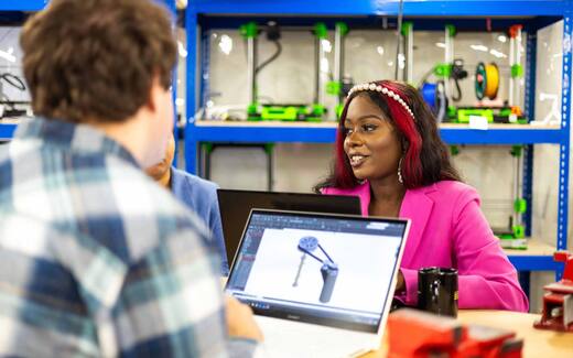 An engineer reviews a 3D product design on a laptop in a prototyping lab