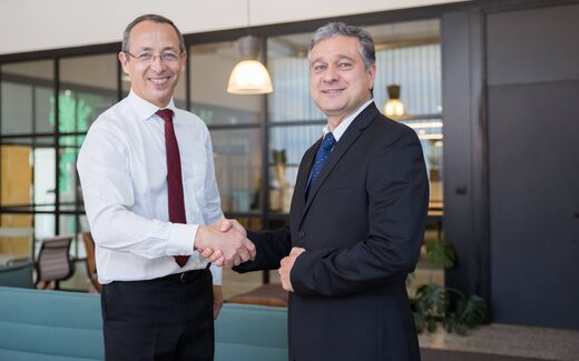 Two colleagues shake hands in a bright office