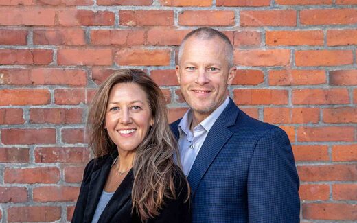 Two business professionals posing together in front of a brick wall, representing Retension Pharmaceuticals' leadership team