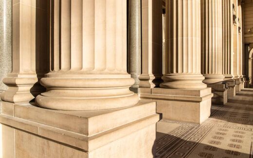A sunlit stone colonnade with rows of fluted columns, a generic architectural image not depicting any Roche facility