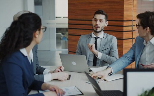 A team reviewing a product rollout around a conference table with laptops open