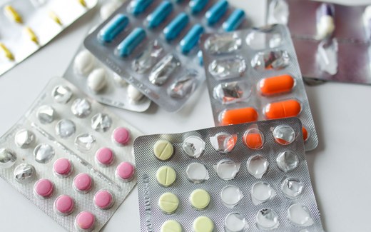 An assortment of pharmaceutical blister packs holding pills and capsules of varying colors spread across a white surface