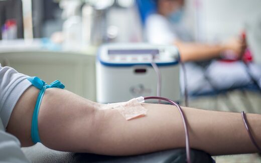 A clinic bedside scene with an IV line taped to a patient's arm, a generic vascular-access stand-in, not a Freesolve RMS procedure