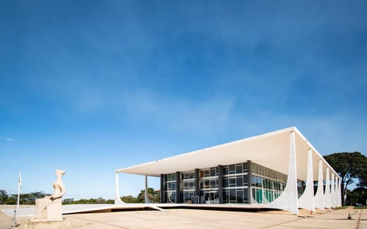 A modernist courthouse with a sweeping cantilevered colonnade beneath a clear blue sky
