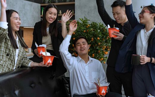 A small office team raising their hands and smiling, a generic stand-in for an approval-day reaction