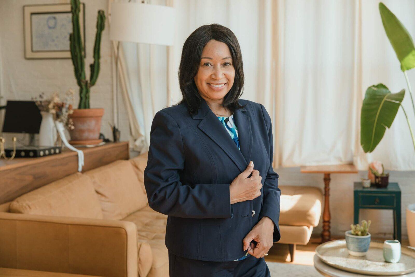 A smiling executive in a navy suit stands in a bright, modern office