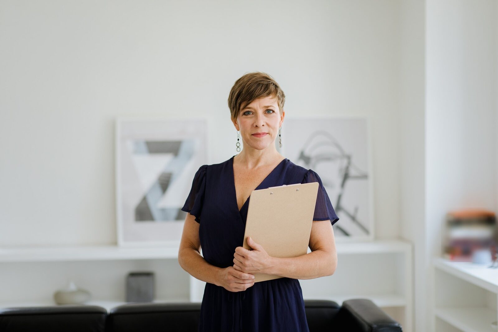 A confident executive holding a clipboard in a bright, minimal office, a generic stand-in for AstraZeneca leadership