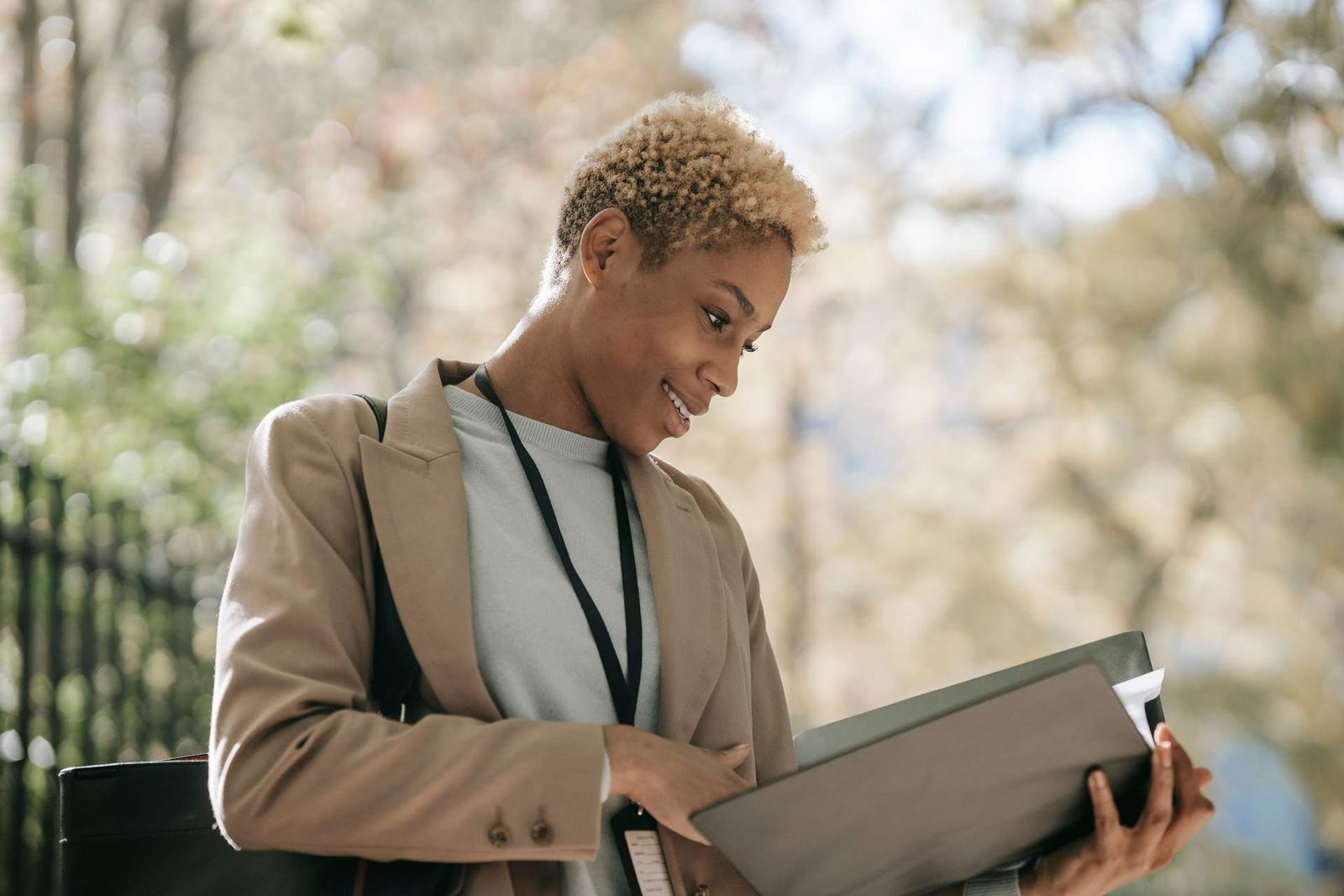 A professional reviews a folder of documents outdoors, lanyard and badge visible