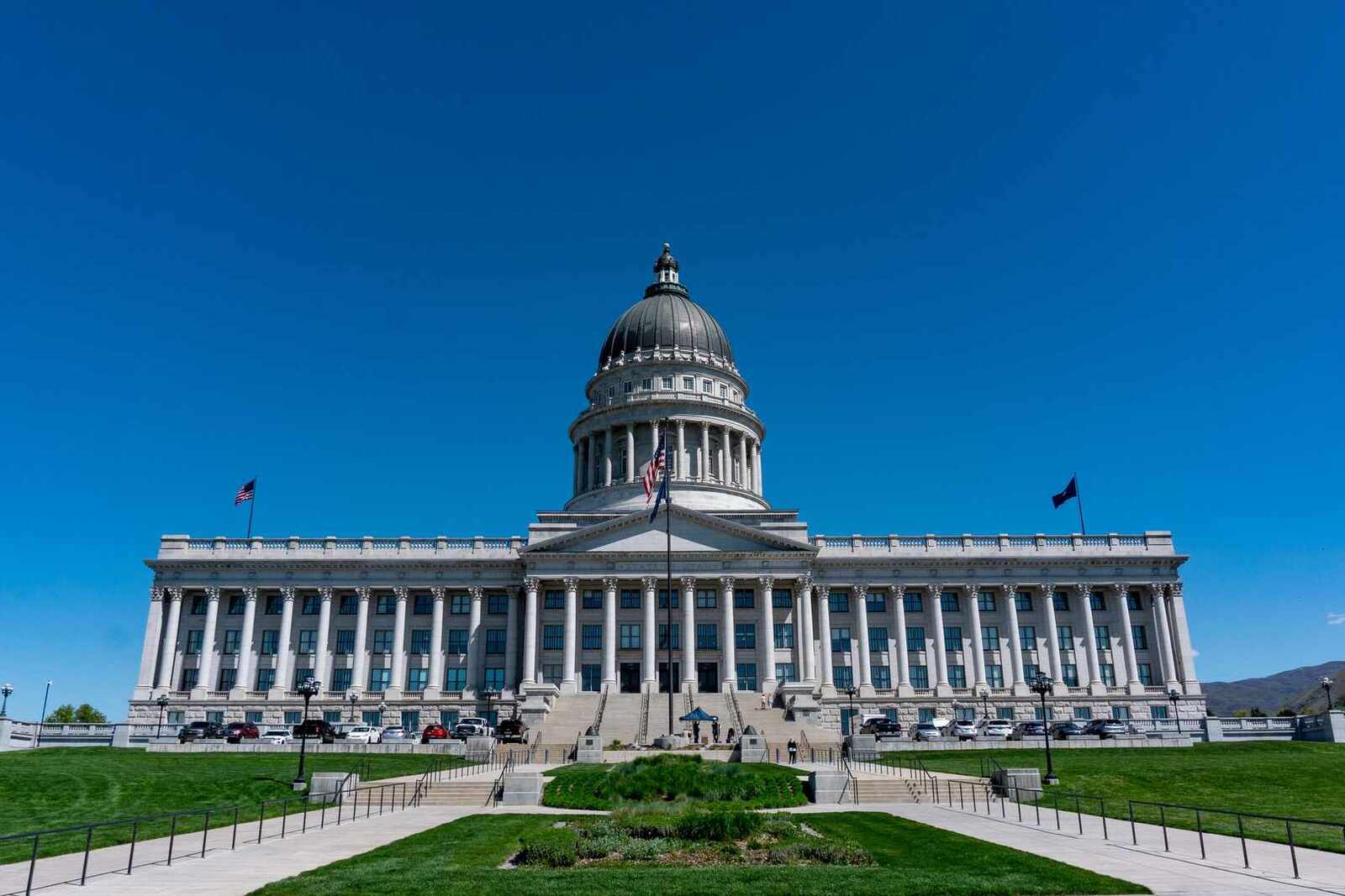 A domed state capitol building photographed from the lawn under a clear blue sky