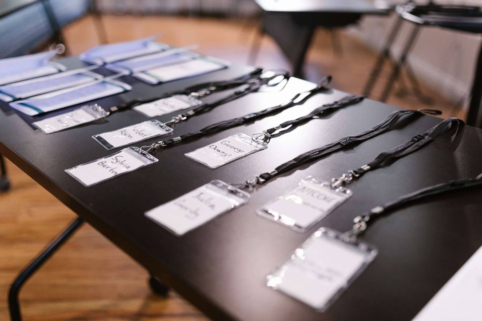 Name badges and lanyards laid out on a registration table beside stacks of folders