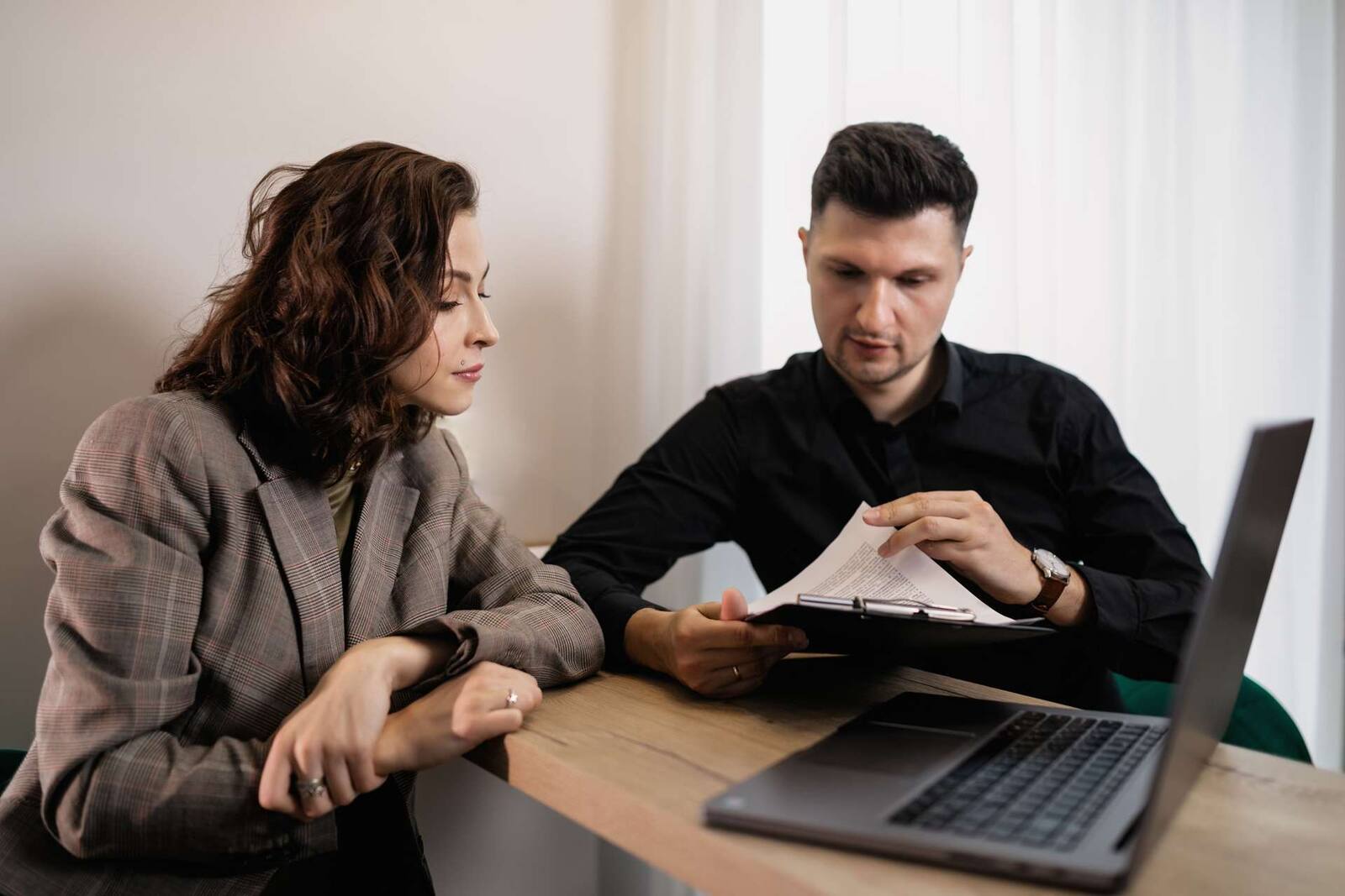 Two people review a printed agenda together across a table, a pen resting on the page between them