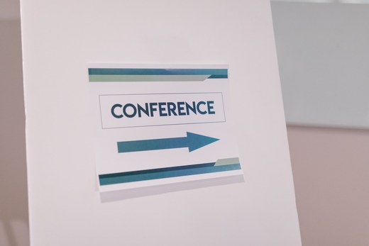 A printed CONFERENCE wayfinding sign with a directional arrow, clean lettering, no people in frame