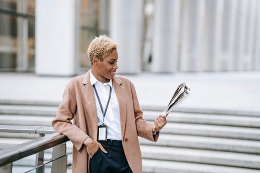 A conference delegate wearing a lanyard reads a folded newspaper outside a venue