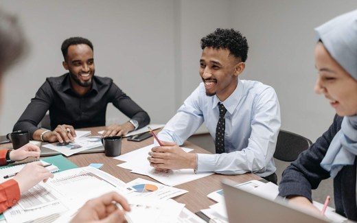 Colleagues review printed charts and data around a bright meeting table