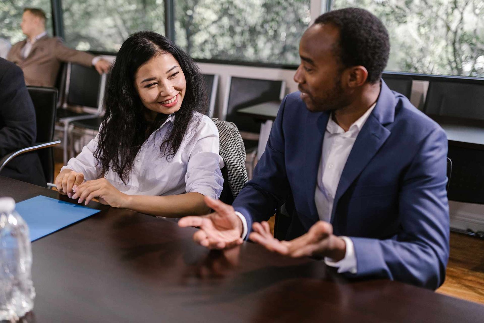 Two conference attendees smiling in conversation at a shared table during a break