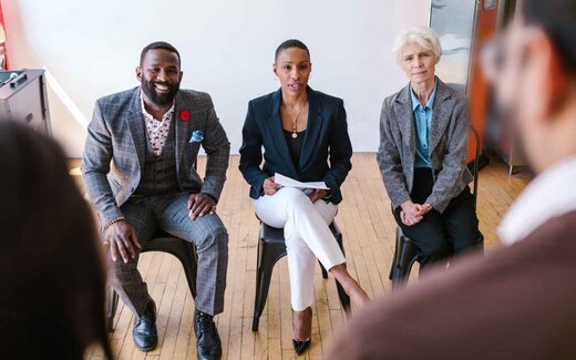Three panellists in business dress seated before an audience during a panel session