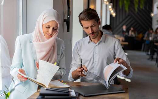 Two colleagues review handwritten notes and a printed document together at a table