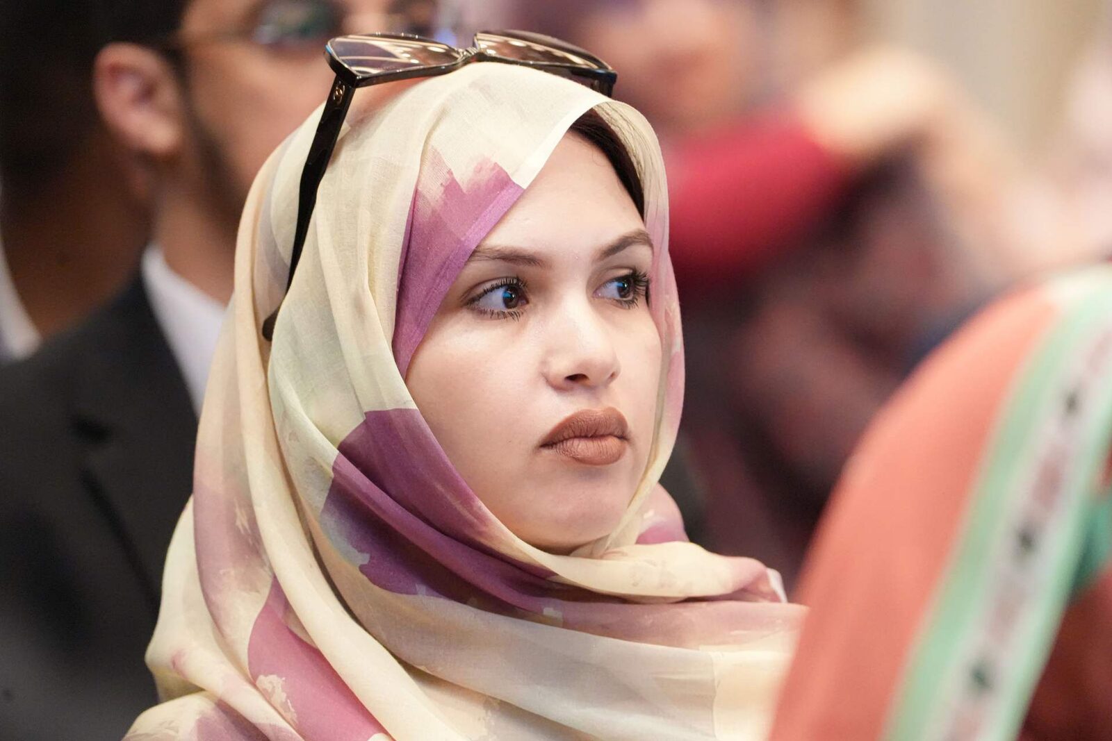 An attentive delegate in a bright conference audience, seated among other attendees