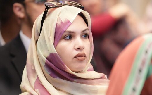 An attentive delegate in a bright conference audience, seated among other attendees