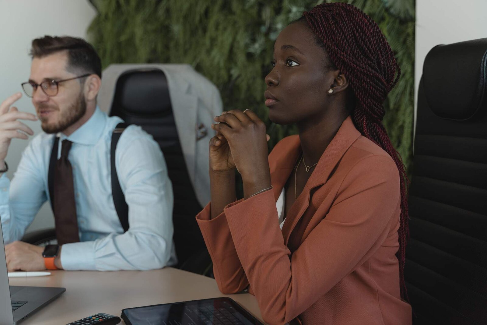 Two delegates listening attentively during a session, one with hands clasped in concentration