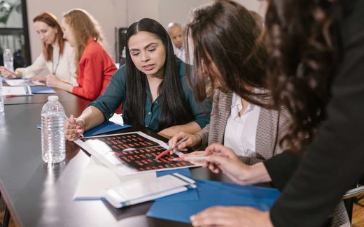 Conference delegates gather around a table, reviewing a printed handout together