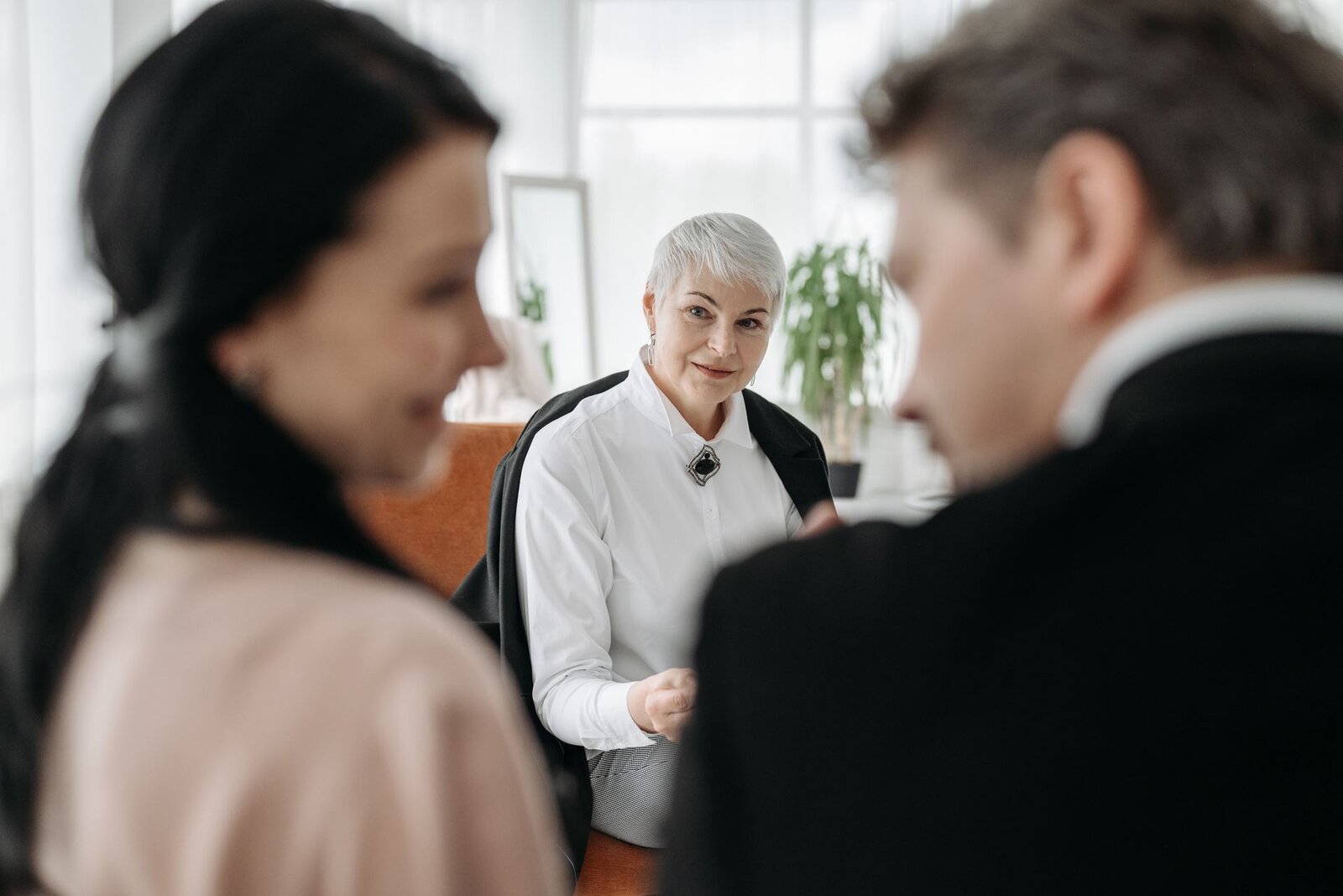 Colleagues in a bright meeting room pause mid-discussion around a small table