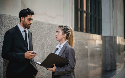 A small group of colleagues in business attire talk through a document at a meeting table