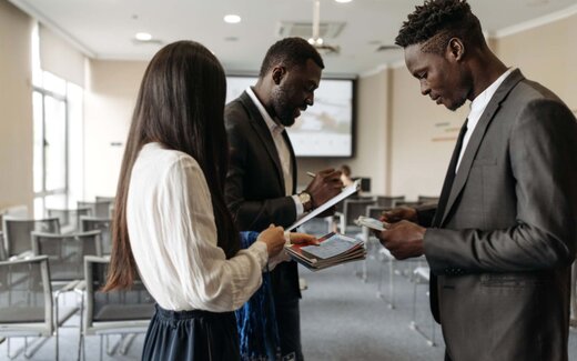 Delegates exchange programmes and lanyards at a training session registration table
