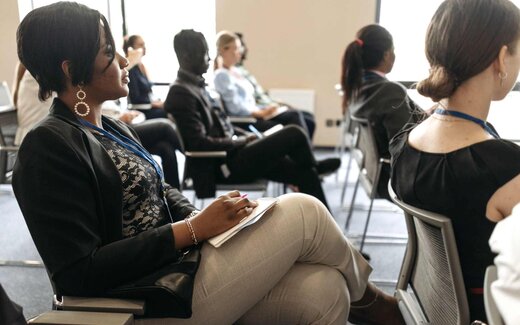 A delegate takes notes in a notebook during a bright, sunlit training session