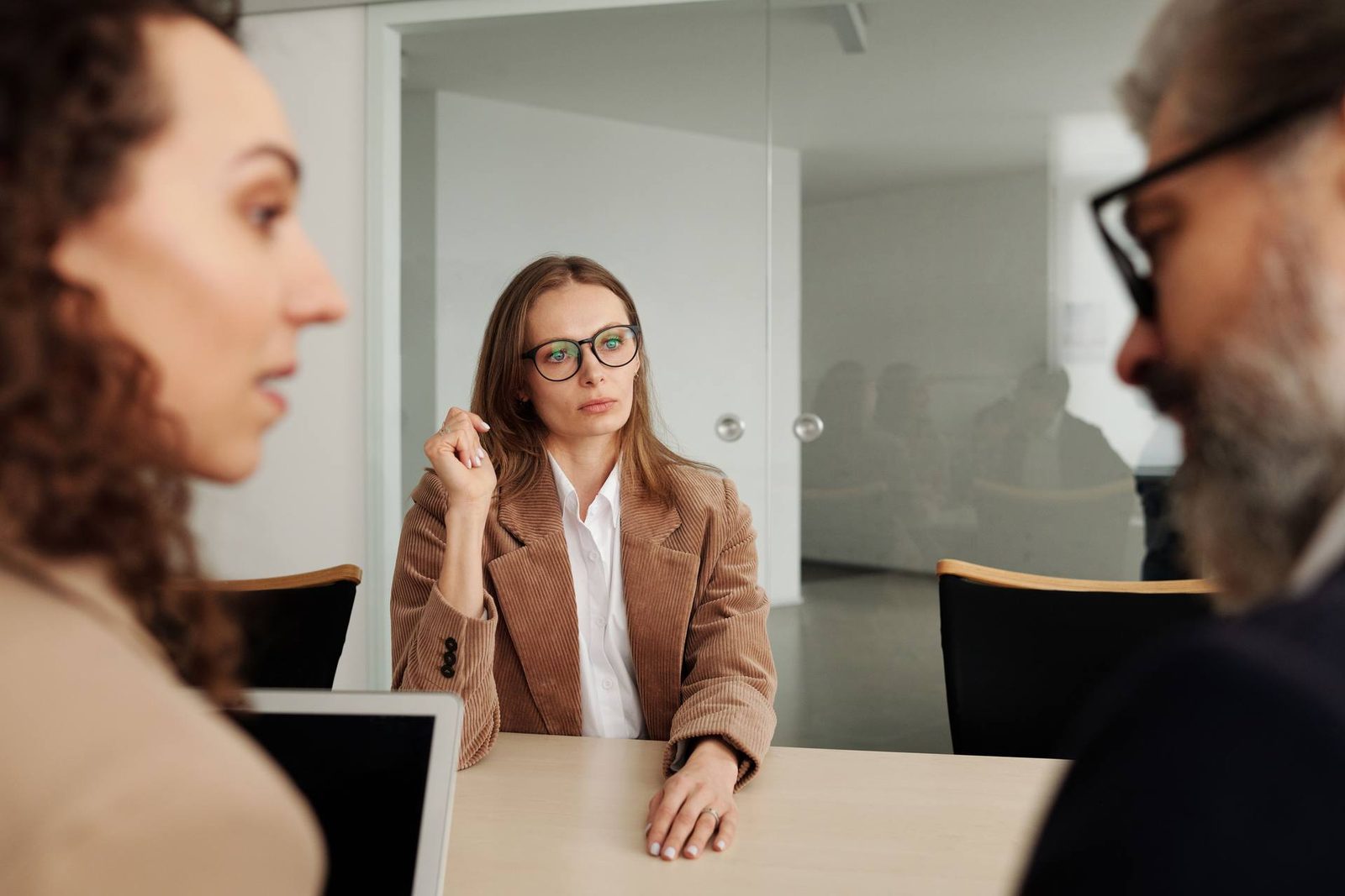 Three colleagues in discussion around a table in a glass-walled meeting room