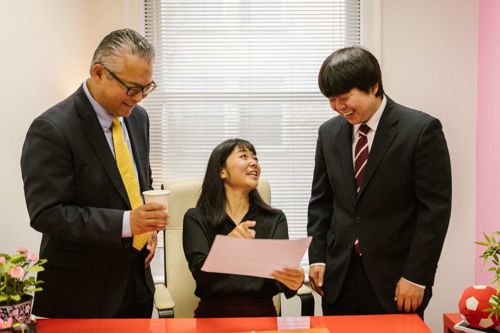 Three colleagues in business attire review a document together in an office